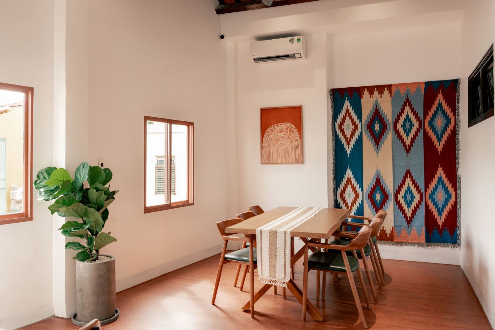 Six-seat wooden table in an air-conditioned room with a kilim wall hanging
