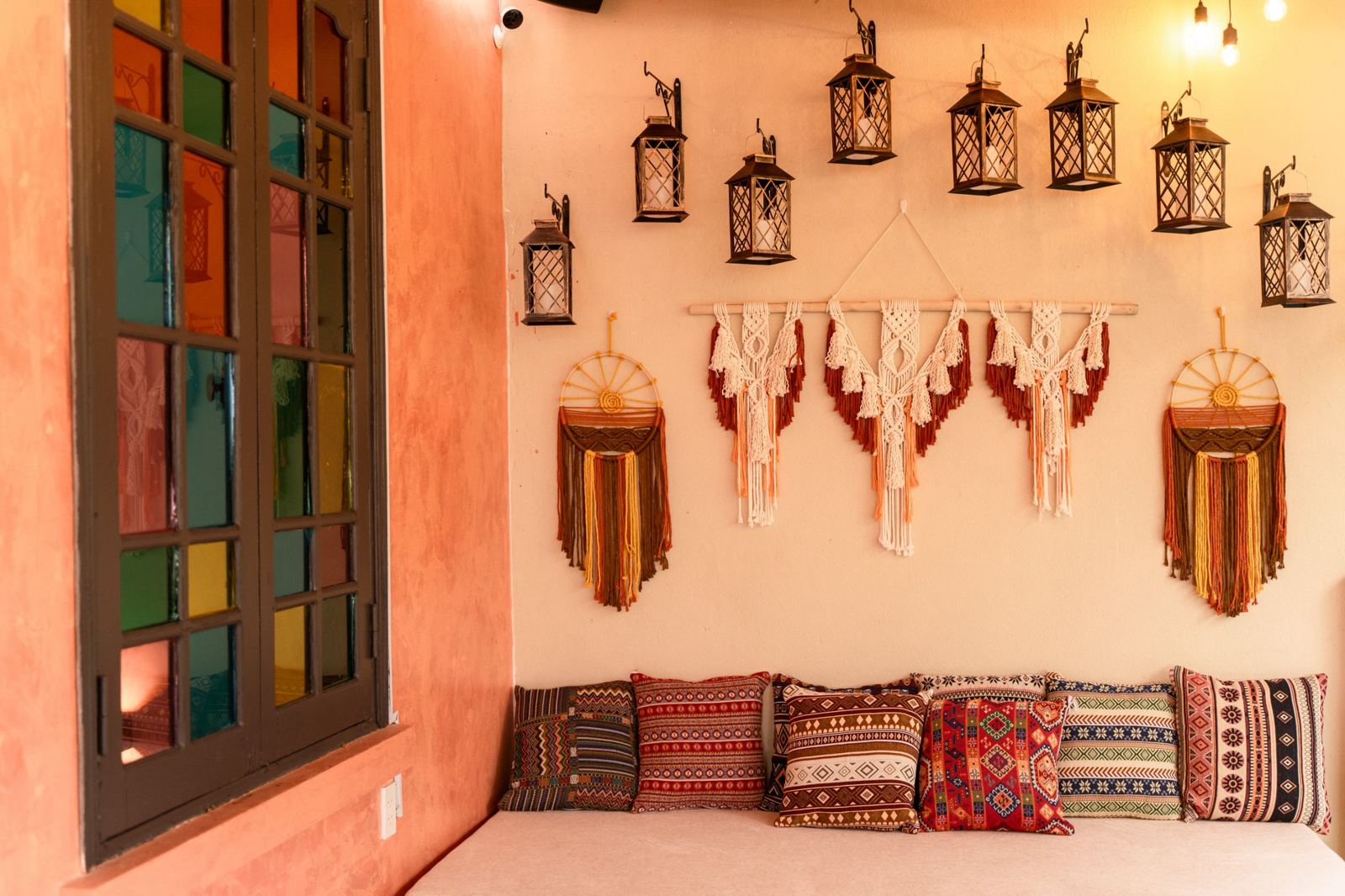 Upstairs lounge corner with patterned cushions, macramé and brass lanterns