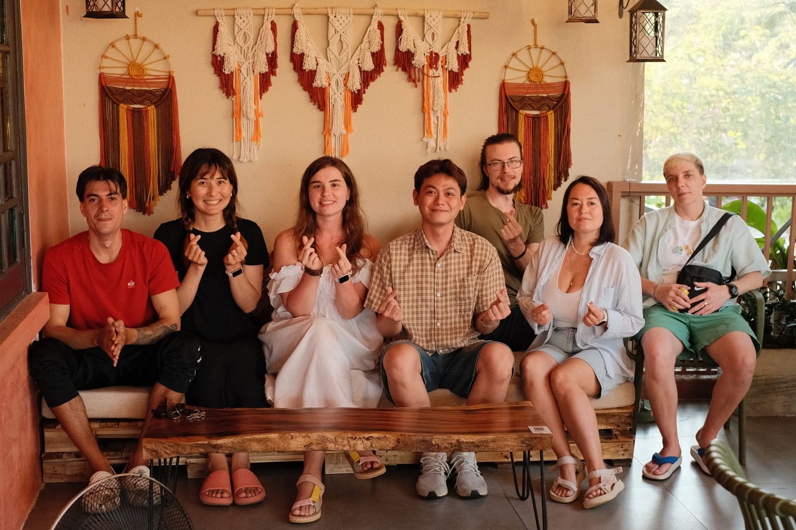 A group of friends on the upstairs lounge sofa making finger hearts