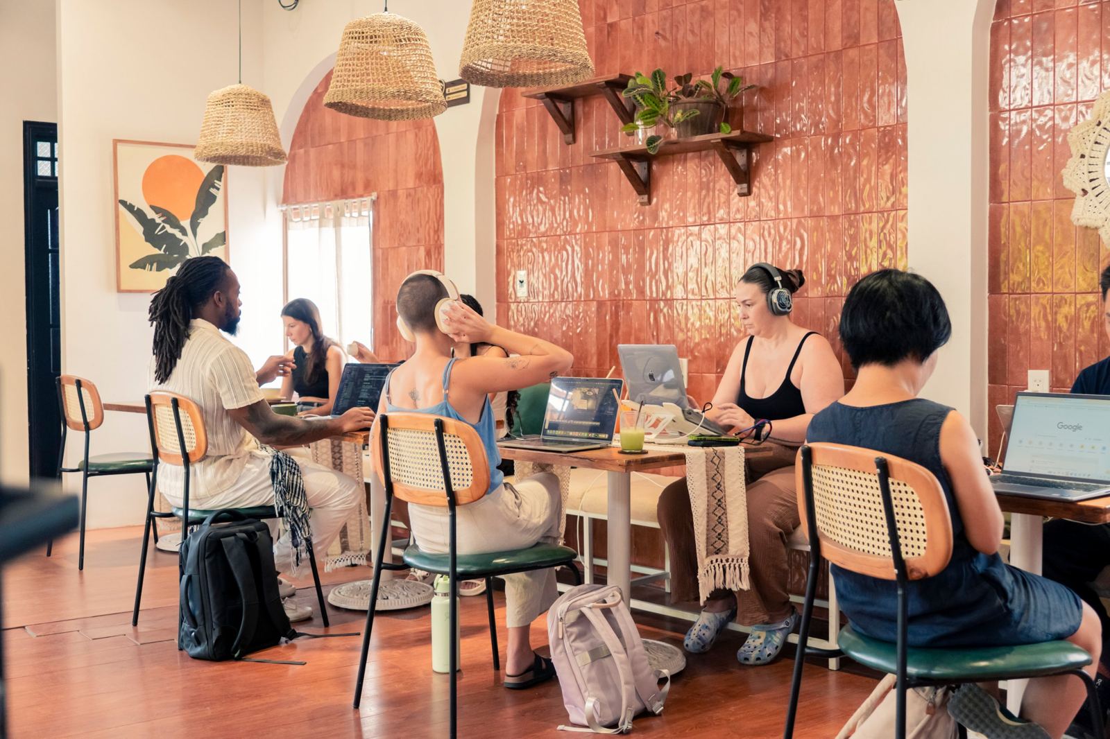 Remote workers on laptops with headphones in the air-conditioned arch room