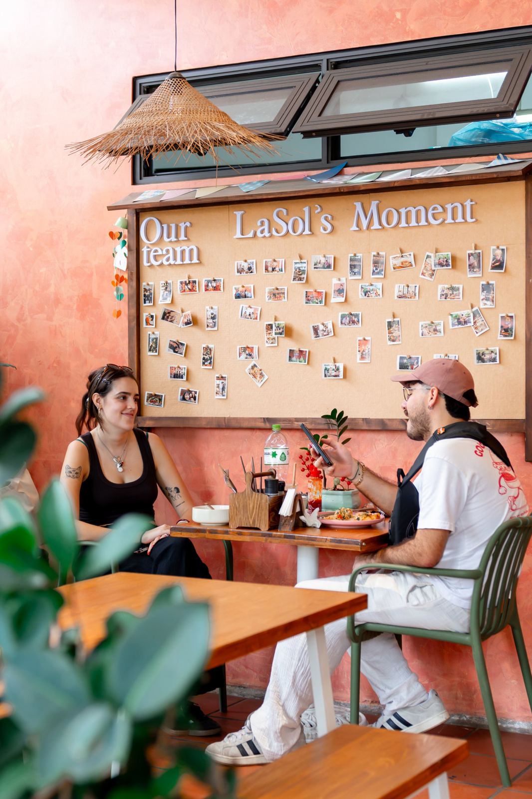 Two guests at a table beneath the LaSol's Moment photo wall