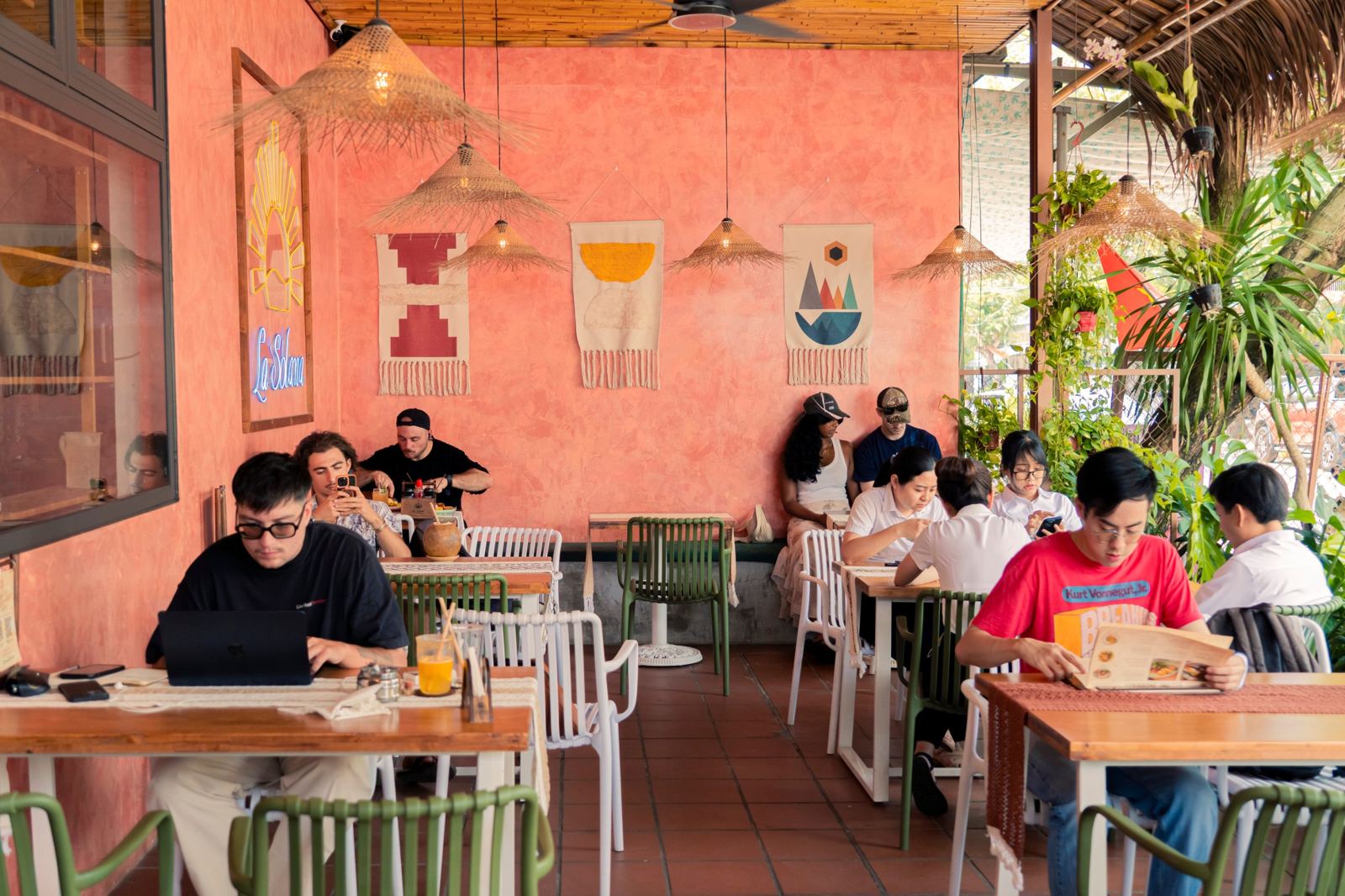 A busy morning on La Solana's ground-floor terrace: guests working on laptops, reading the menu and eating brunch under rattan lamps