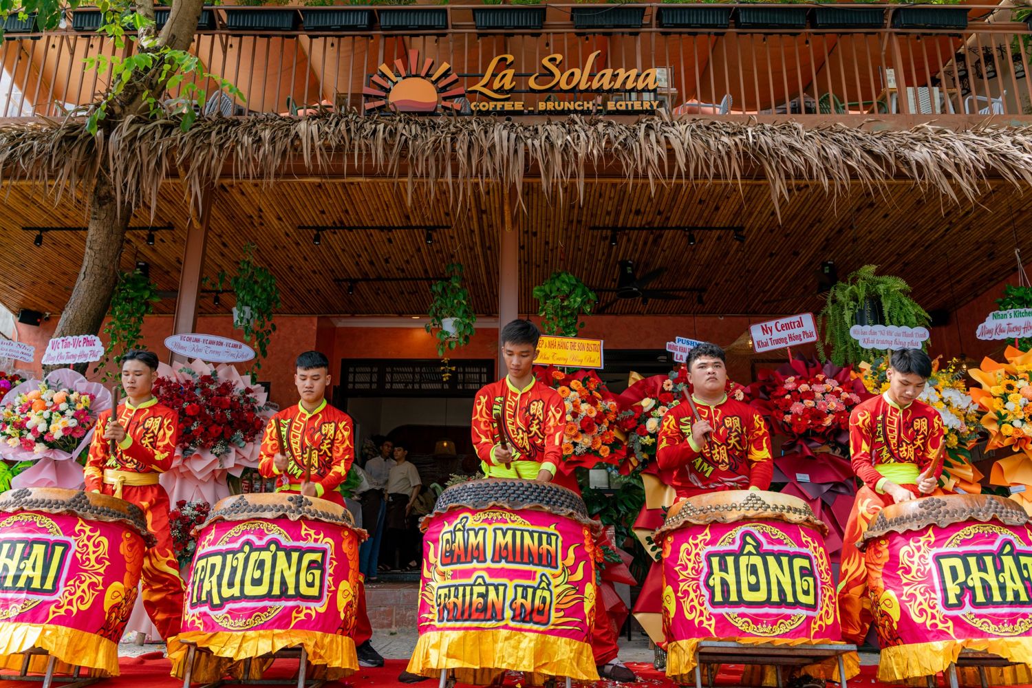 Drummers under the La Solana sign spelling Khai Trương Hồng Phát